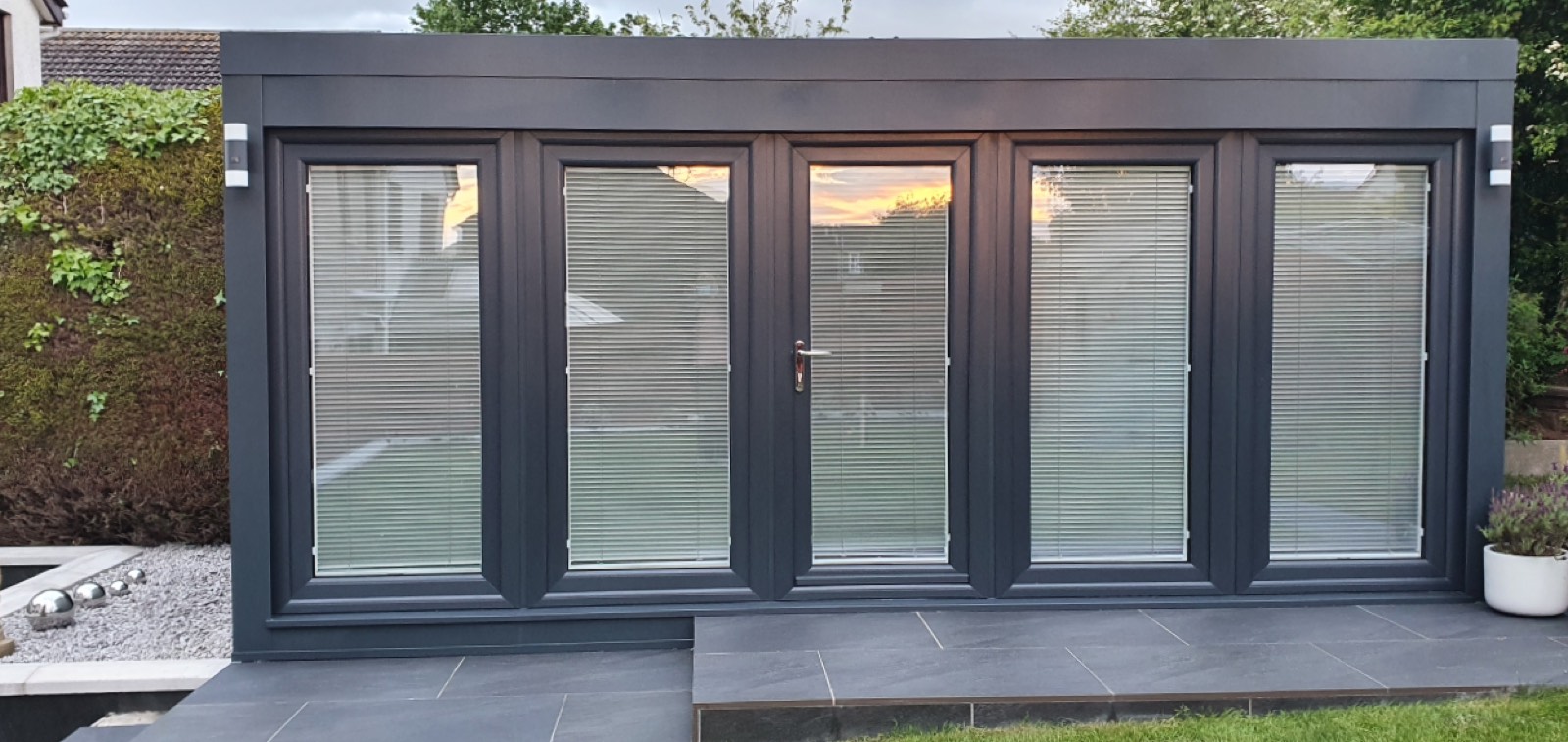 A Booths anthracite-grey QCB garden office installed in a Scottish garden at dusk